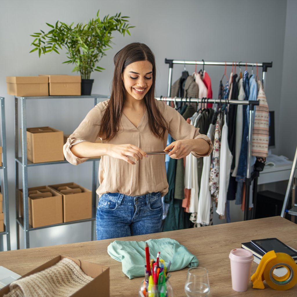 Young small business owner working at home, taking picture of packaging.